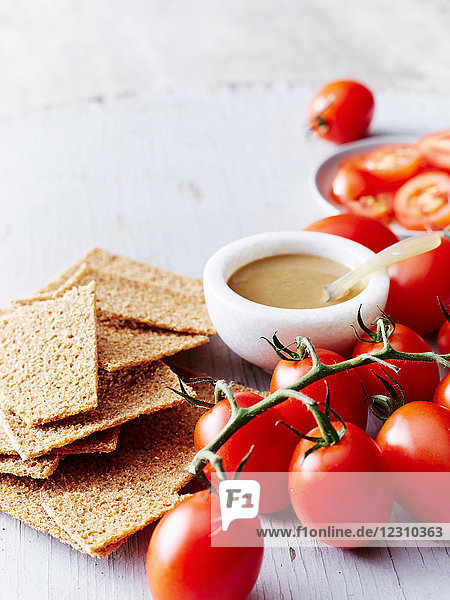 Stilleben mit Tahini Roggenkräckern und Strauchtomaten