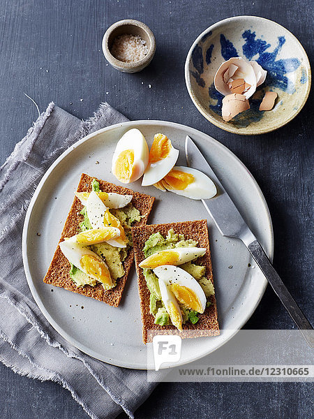 Still life of rye crackers with boiled sliced eggs on plate  overhead view