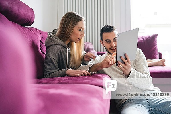 Paar entspannt sich auf dem Sofa mit einem digitalen Tablett