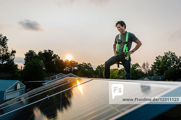 Auf dem Hausdach stehender Handwerker  der Sonnenkollektoren installiert