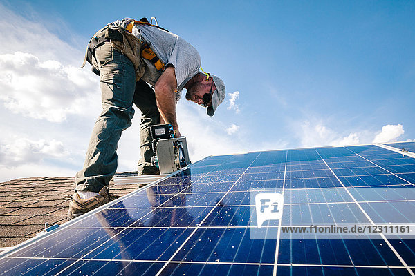 Handwerker  der Sonnenkollektoren auf dem Hausdach installiert  niedriger Blickwinkel