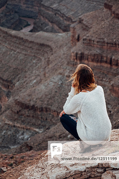 Junge Frau in abgelegener Umgebung  auf Felsen kauernd  Blick in die Ansicht  Rückansicht  Mexican Hat  Utah  USA