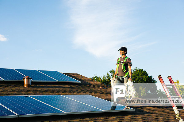 Auf dem Hausdach stehender Handwerker  der Sonnenkollektoren installiert