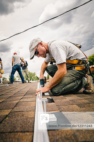 Handwerker  der Sonnenkollektoren auf dem Hausdach installiert  niedriger Blickwinkel