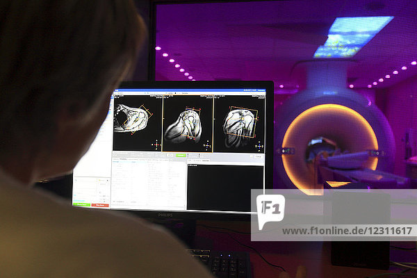Ärzte prüfen einen Scan auf einem Computer mit einem Patienten im MRT-Scanner im Hintergrund