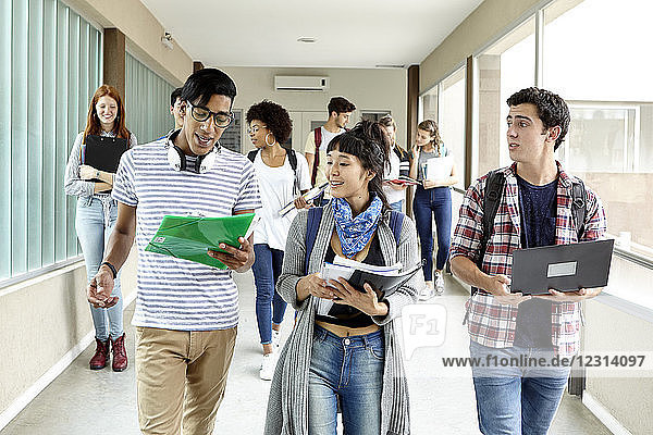 Students chatting while walking together in school corridor