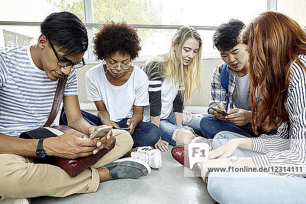 Schüler sitzen zusammen und benutzen Smartphones