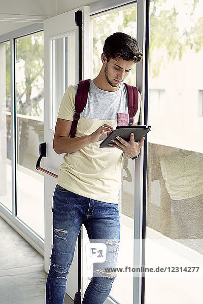 College-Student schaut zwischen den Vorlesungen auf ein digitales Tablet