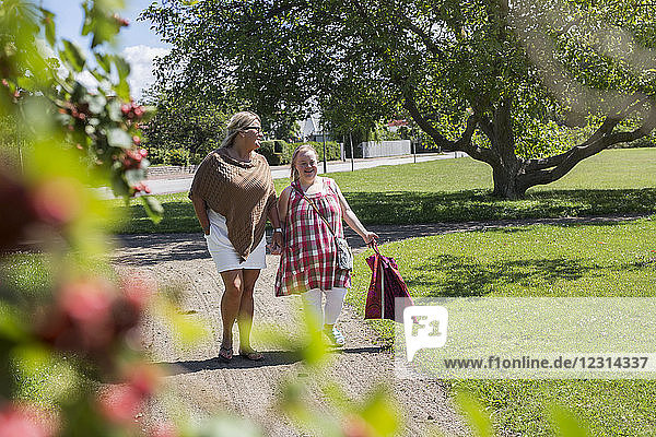Mother and daughter with down syndrome walking in park