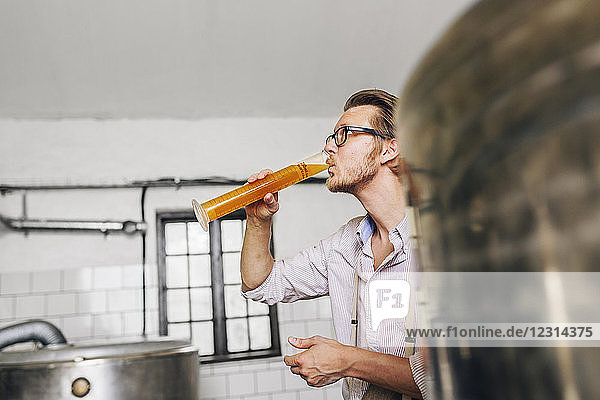 Brewery worker drinking beer from beaker