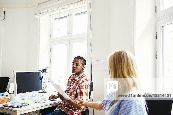 Coworker passing document to colleague in office