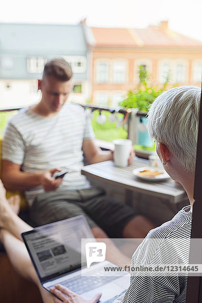 Couple using mobile devices on balcony