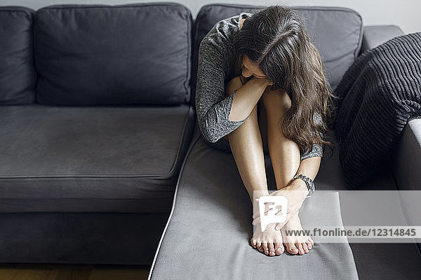 Pensive woman sitting on sofa