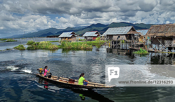 Dorf Kela; Shan-Staat  Myanmar (Burma)  Asien; Stelzenhäuser; steht im Wasser; Einheimische in einem Holzboot paddeln auf dem Inle-See