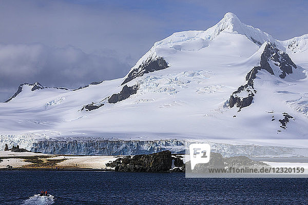 Tourists on a zodiac boat approach Half Moon Island  Livingston Island mountain backdrop  South Shetland Islands  Antarctica  Polar Regions