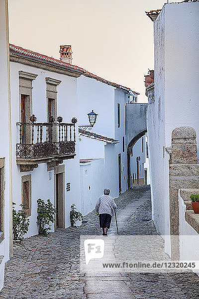 An old woman walking along an alley in the mountain village of Marvao in the Alentejo  Portugal  Europe