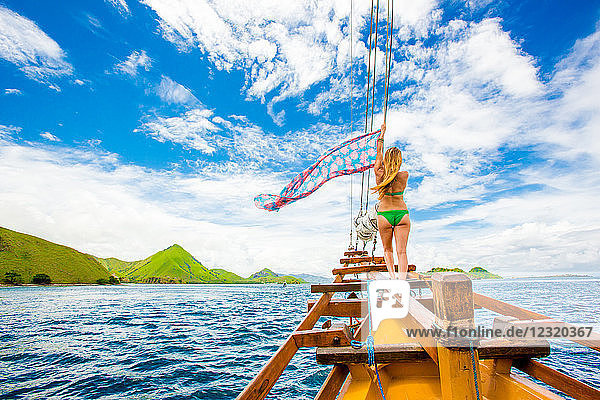 Girl perched on bow of Phinisi Boat  sailing through Komodo National Park  Indonesia  Southeast Asia  Asia