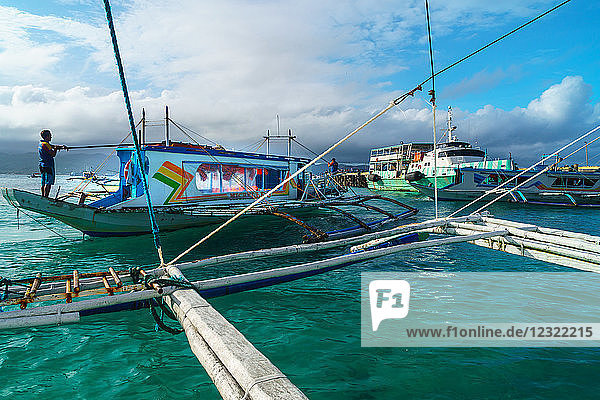 Bangkas (Auslegerkanus) und die alte Fähre konkurrieren um den Landeplatz im Hafen  Borocay Island  Philippinen  Südostasien  Asien