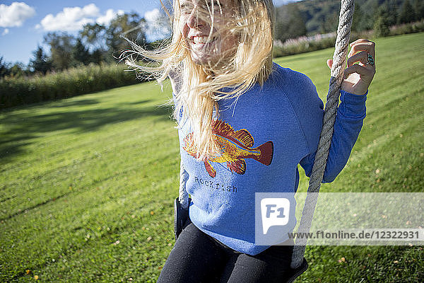 Young woman with long  blond hair on a swing  South-central Alaska; Homer  Alaska  United States of America