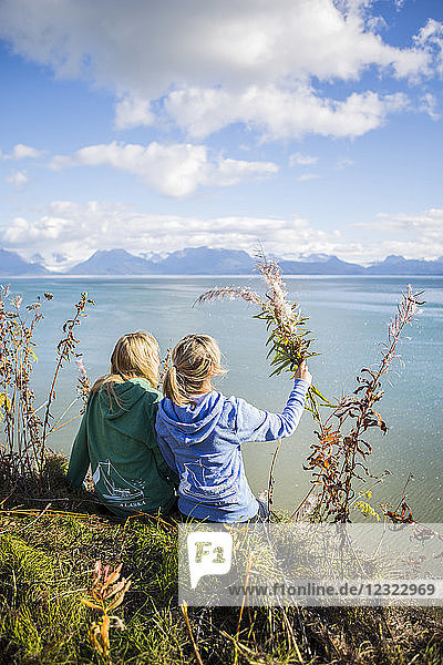 Zwei Frauen sitzen an einem Herbsttag auf einer Klippe mit Blick auf die Kachemak Bay  Süd-Zentral-Alaska; Homer  Alaska  Vereinigte Staaten von Amerika