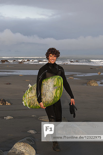Surfer with board on beach  Southeast Alaska; Yakutat  Alaska  United States of America