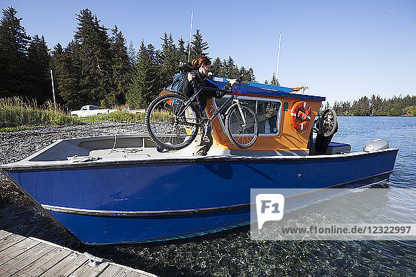 Frau lädt ihr Fahrrad auf ein Wassertaxi  Kenai-Halbinsel  Süd-Zentral-Alaska; Alaska  Vereinigte Staaten von Amerika