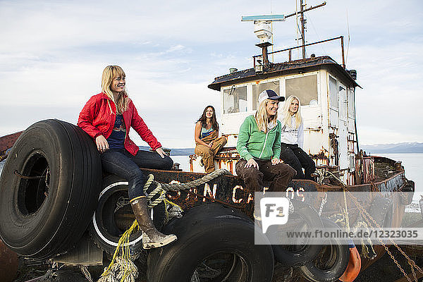 Gruppe von Freunden  die auf einem baufälligen Fischerboot entlang der Küste Alaskas abhängen  Süd-Zentral-Alaska; Homer  Alaska  Vereinigte Staaten von Amerika