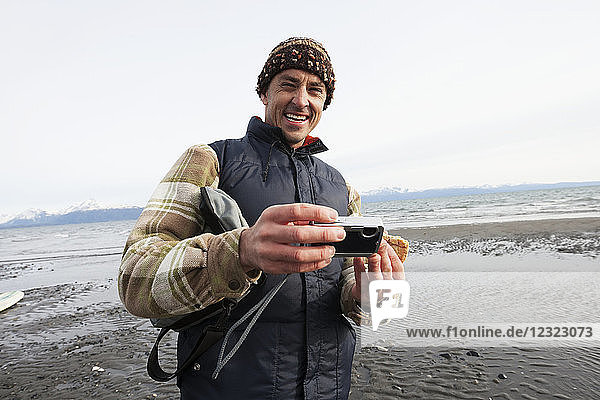 Mann am Strand von Homer mit einer Digitalkamera  Süd-Zentral-Alaska; Alaska  Vereinigte Staaten von Amerika