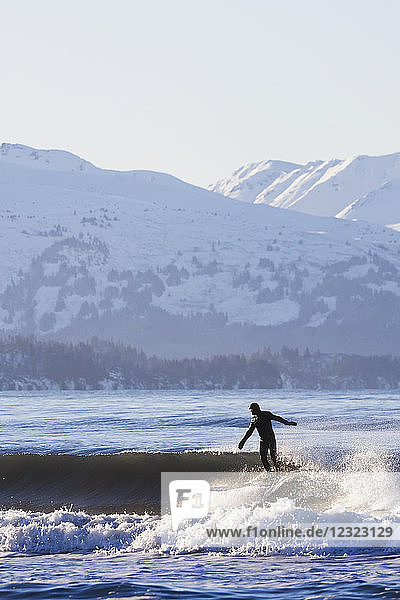 Surferin reitet auf einer Welle in der Kachemak Bay  Süd-Zentral-Alaska; Homer  Alaska  Vereinigte Staaten von Amerika