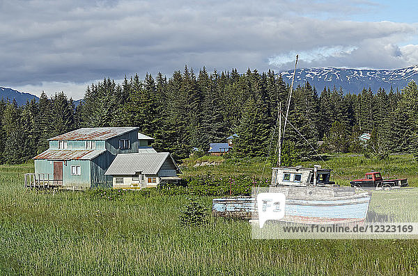 Rustic wooden boat and home on the grass shore near ferry dock Southeast Alaska; Gustavus Alaska United States of America