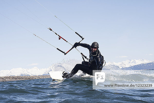 Man kitesurfing with Kenai Mountains in the background  Homer  South-central Alaska; Homer  Alaska  United States of America