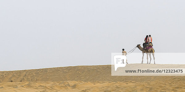 Ein Paar auf einer Kamelsafari in den Lakhmana-Dünen; Damodara  Rajasthan  Indien