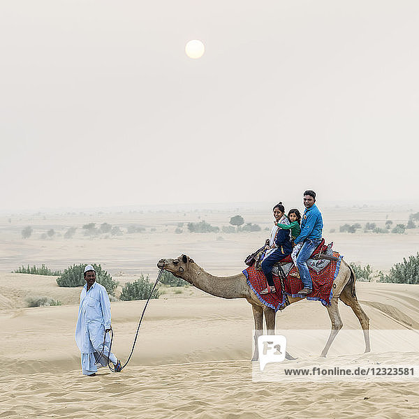 Eine Familie auf einer Kamelsafari in den Lakhmana-Dünen; Damodara  Rajasthan  Indien