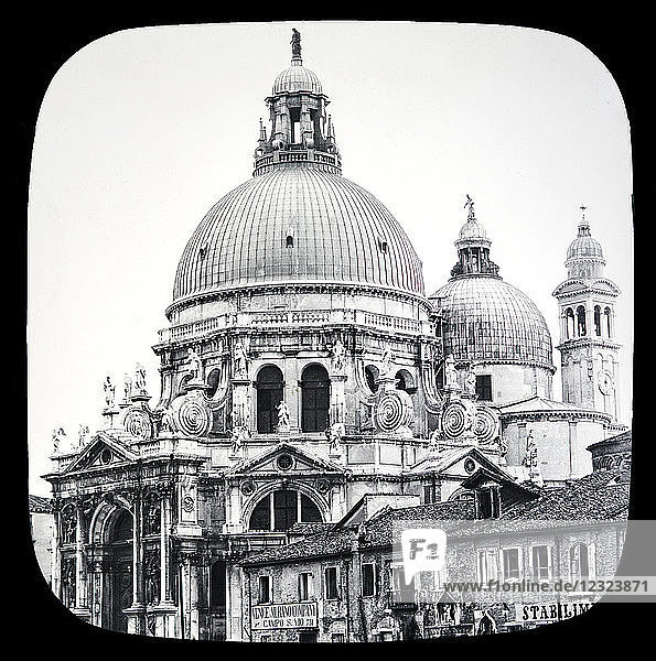 Magic lantern slide circa 1900.Victorian/Edwardian.Social History. The Beauties of Venice photographs created in 1888 Joseph John William ACWORTH F.I.C.  F.C.S.J. The Beauties of Venice . Salute Church  which was built during the years 1631 and 1682 as a votive offering by the· Venetians after one of the plagues which cost Venice the lives of 40 000 of her citizens.With its magnificent domes crowned with statuary  its glittering white marble column  and its chaste and elegantly wrought ornamentation  it is one of the landmarks of the city. Its foundation is said to consist of more than a million piles. The interior is very beautiful  and contains many fine works of art  including a number by Titian and other painters.