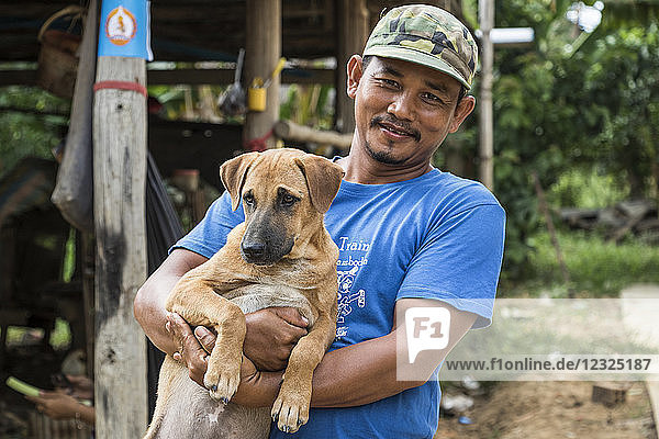 Kambodschanischer Mann hält einen Hund; O Sra Lav  Battambang  Kambodscha