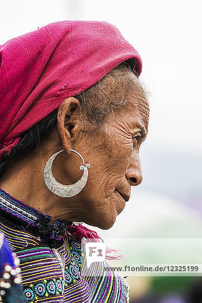 Porträt einer älteren Frau mit Kopftuch und Ohrringen und buntem Kleid; Bac Ha  Lao Cai  Vietnam