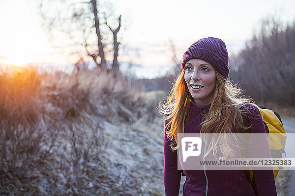 Eine junge Frau trägt einen Rucksack und geht bei Sonnenaufgang spazieren; Anchorage  Alaska  Vereinigte Staaten von Amerika