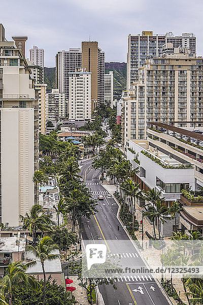 Eastward view down Kuhio Avenue in Waikiki  Honolulu  Hawaii  with Diamond Head on horizon visible between buildings. The new International Market Place with it's rooftop parking is in the foreground on the righthand side. It opened in 2016; Honolulu  Oahu  Hawaii  United States of America