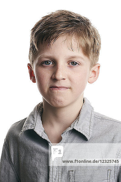 Porträt eines kleinen Jungen mit entschlossenem Gesichtsausdruck auf weißem Hintergrund
