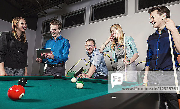 A group of young millennial business professionals playing a game of pool together on a work break; Sherwood Park  Alberta  Canada