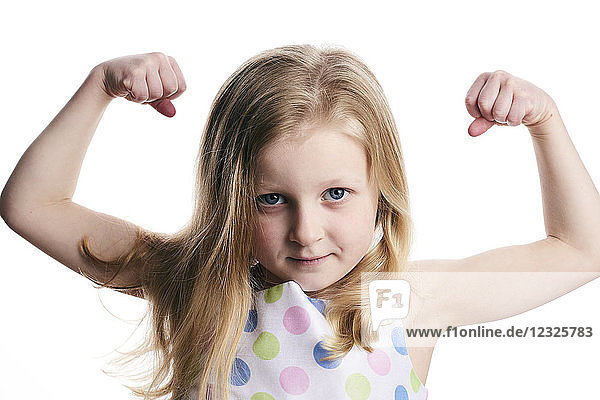 A young girl with blond hair shows her muscles on a white background