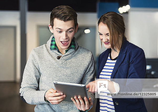 Zwei junge Geschäftsleute sind überrascht von dem  was sie auf dem Tablet an ihrem Arbeitsplatz sehen; Sherwook Park  Alberta  Kanada