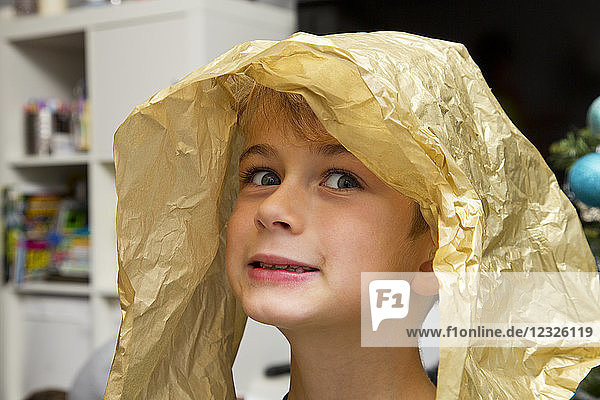 Porträt eines kleinen Jungen mit einem Stück Geschenkpapier auf dem Kopf  der ein dummes Gesicht macht; Langley  British Columbia  Kanada