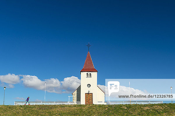 Mädchen geht an kleiner Kirche vorbei; Langaholt,  Island