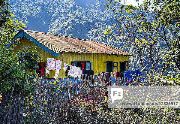 Ein leuchtend gelbes Haus mit blauen Verzierungen und einer Wäscheleine  die draußen im Himalaya hängt; Westbengalen  Indien