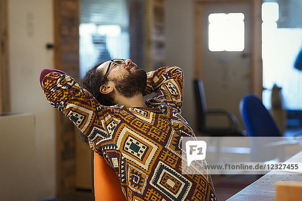 Creative businessman stretching at desk in office