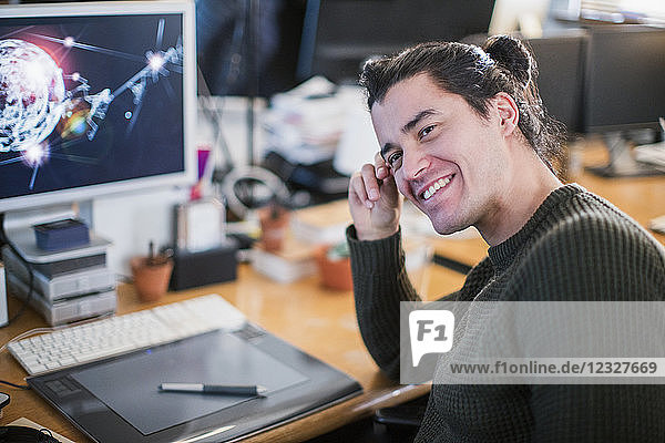 Portrait smiling  confident male graphic designer working at desk