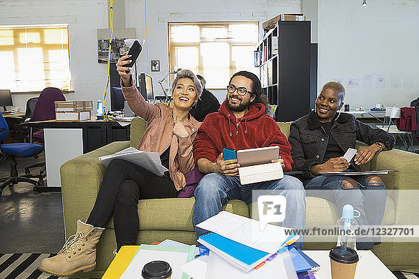 Happy creative business people taking selfie in casual open plan office
