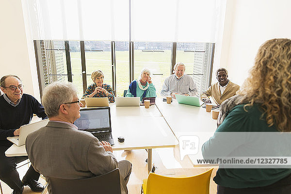 Senior business people using digital tablets and laptops in conference room meeting