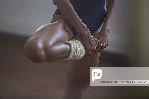 Strong young female dancer stretching leg